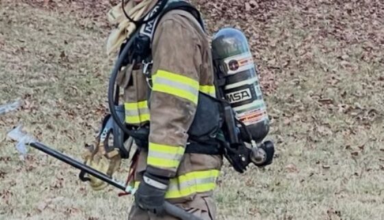 firefighter in full uniform walking away from the camera, smiling back.